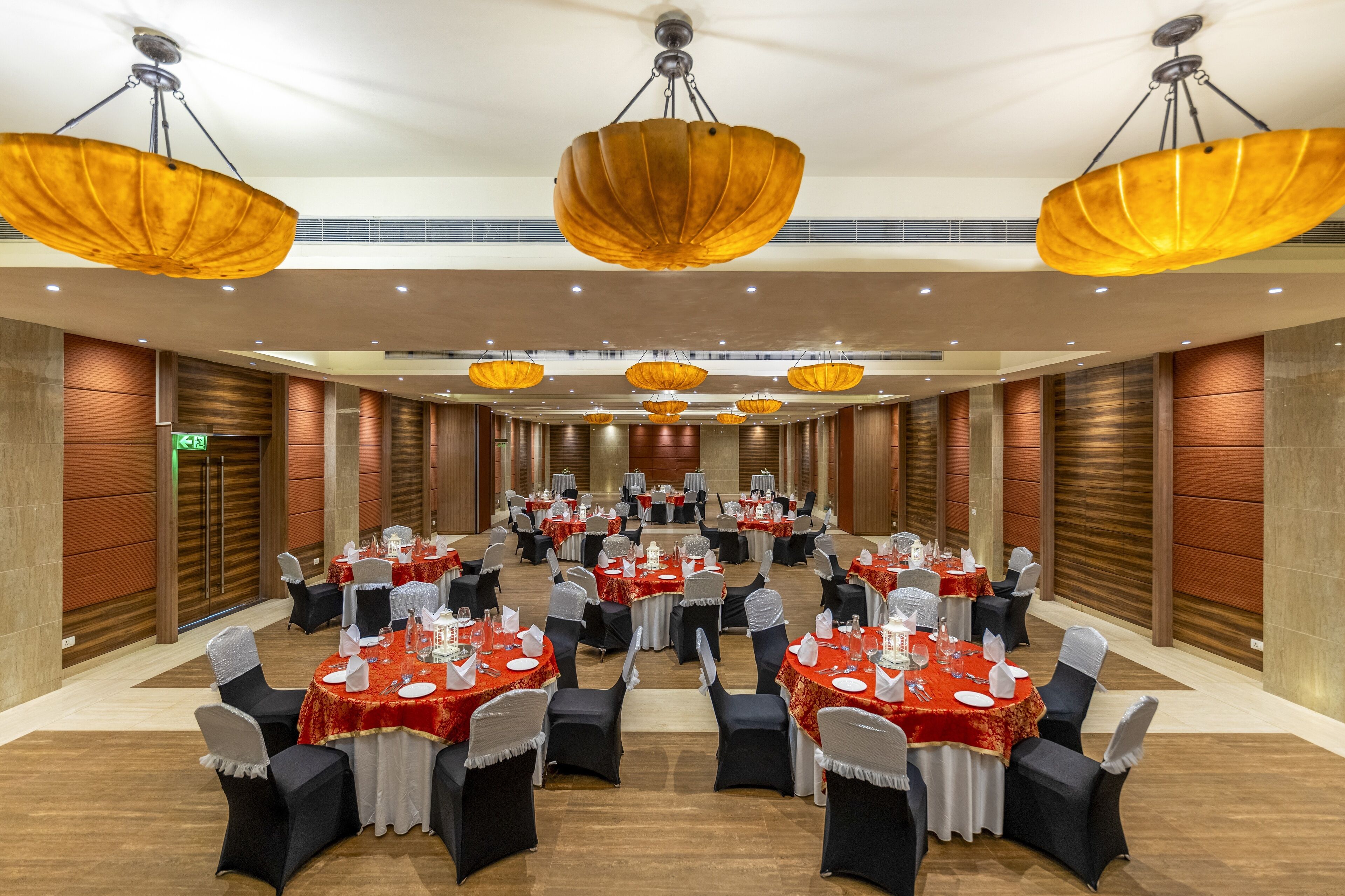 A large conference room with multiple round tables, each set with white tablecloths and black chairs.