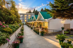 Un pasillo de hotel con una fila de habitaciones, un camino de piedra y plantas en macetas a lo largo de las paredes.