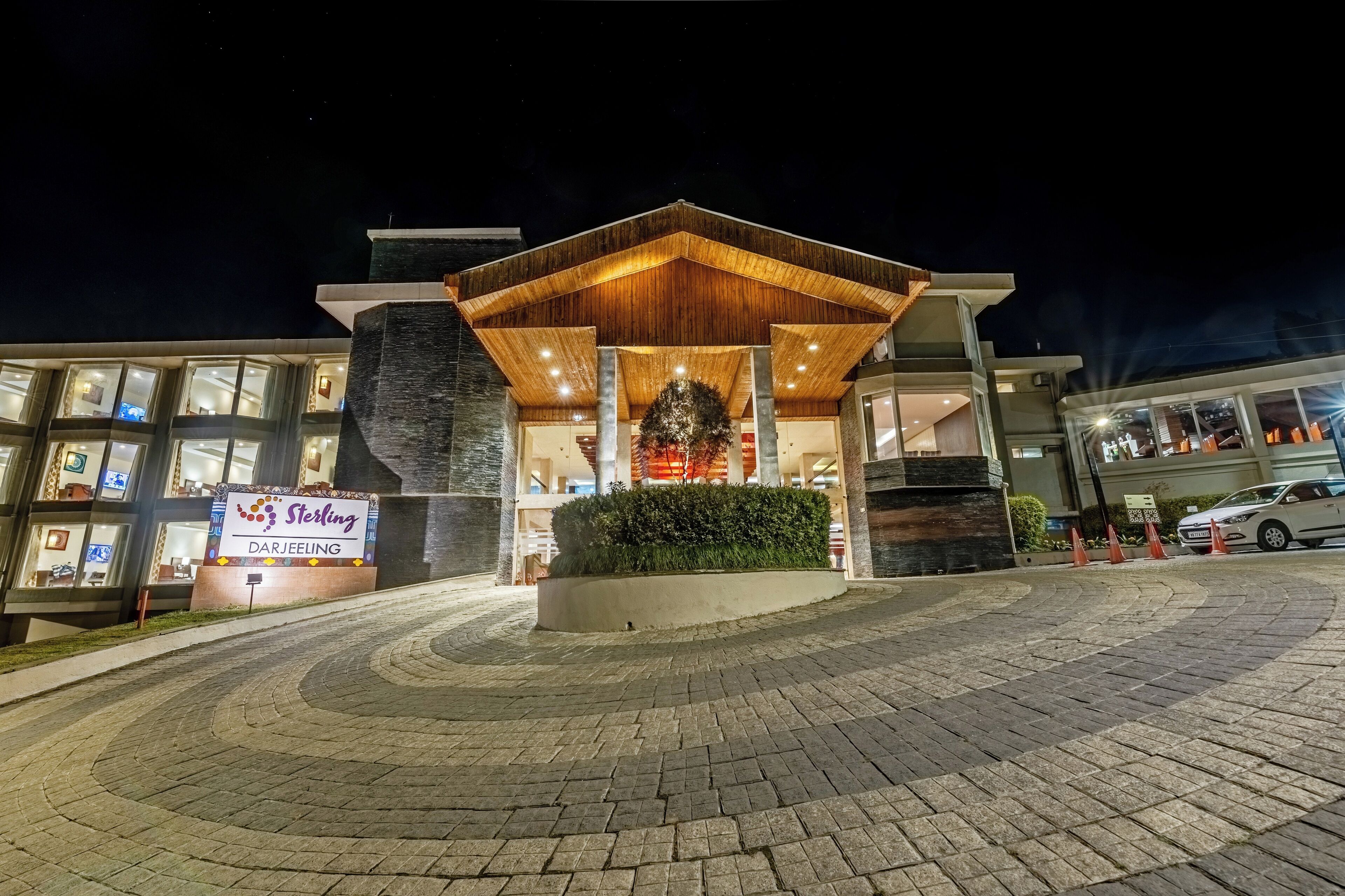 A modern hotel entrance with a wooden canopy, a Christmas tree, and a sign reading "Sterling Darjeeling."