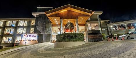 A modern hotel entrance with a wooden canopy, a Christmas tree, and a sign reading "Sterling Darjeeling."