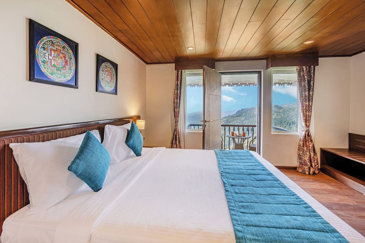 A hotel room with a large bed, a wooden ceiling, and two windows with curtains.