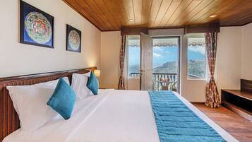 Quarto de hotel com uma cama grande, teto de madeira e duas janelas com cortinas.