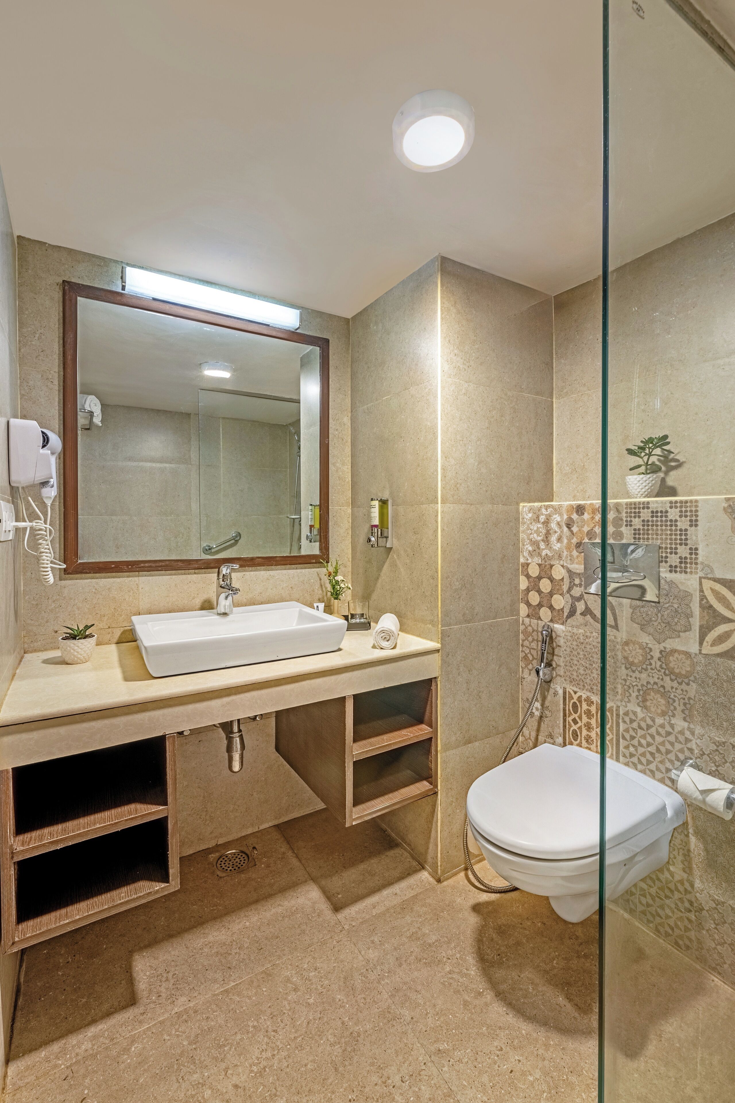A modern bathroom with a large mirror, a sink, a toilet, and a shower area.