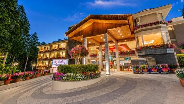 A hotel with a modern architectural design, featuring a prominent entrance with a wooden canopy, multiple balconies with flower arrangements, and a landscaped area with potted plants. - Sterling Darjeeling (Darjeeling)