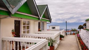 Fileira de casas com telhados verdes e grades brancas, um caminho e vasos com plantas.