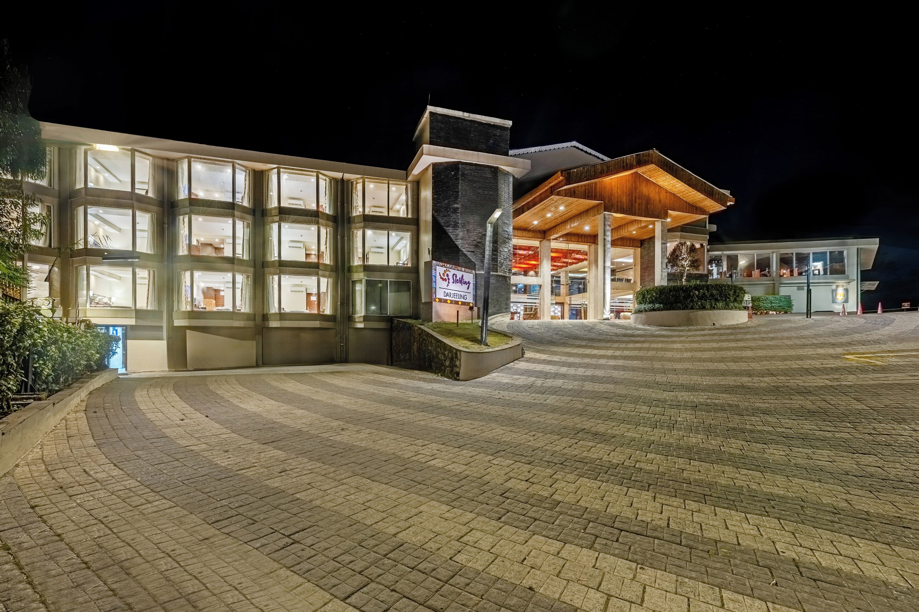 Hotel com design moderno, destacando uma grande fachada de vidro e área de entrada coberta.