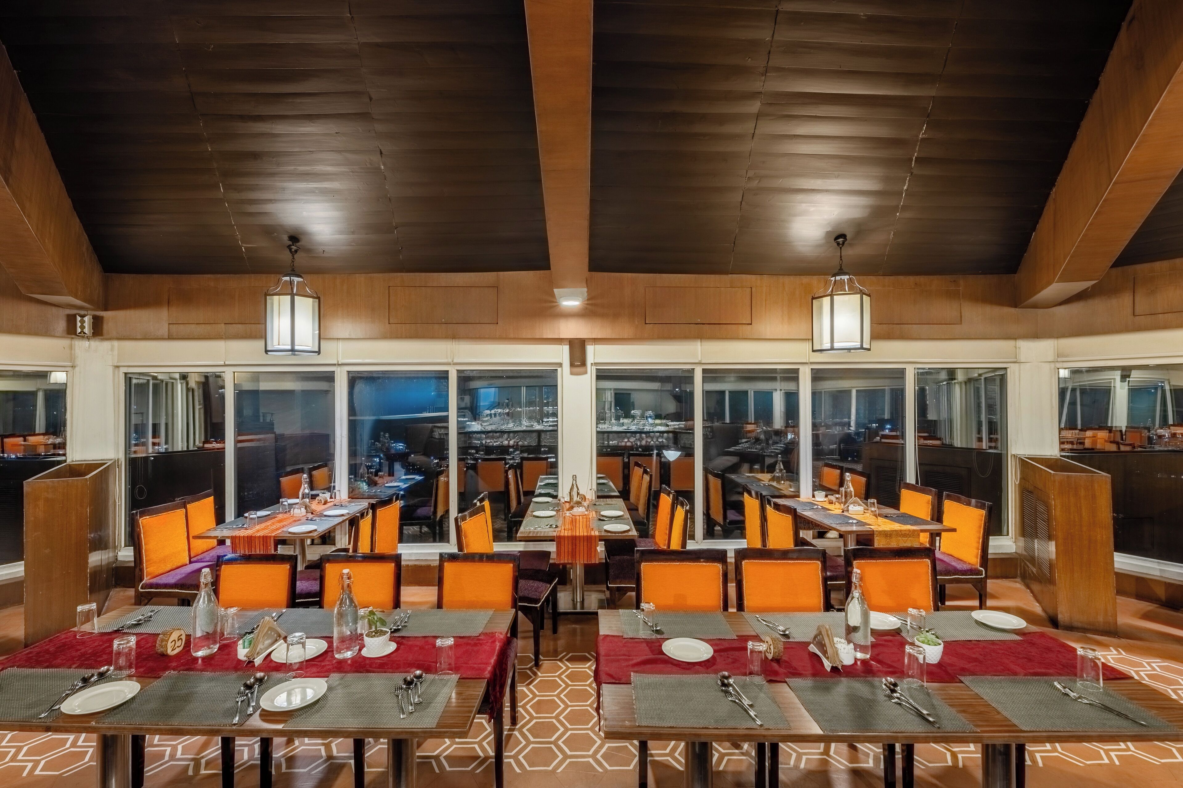 A restaurant with multiple dining tables, chairs, and a high ceiling with wooden beams.