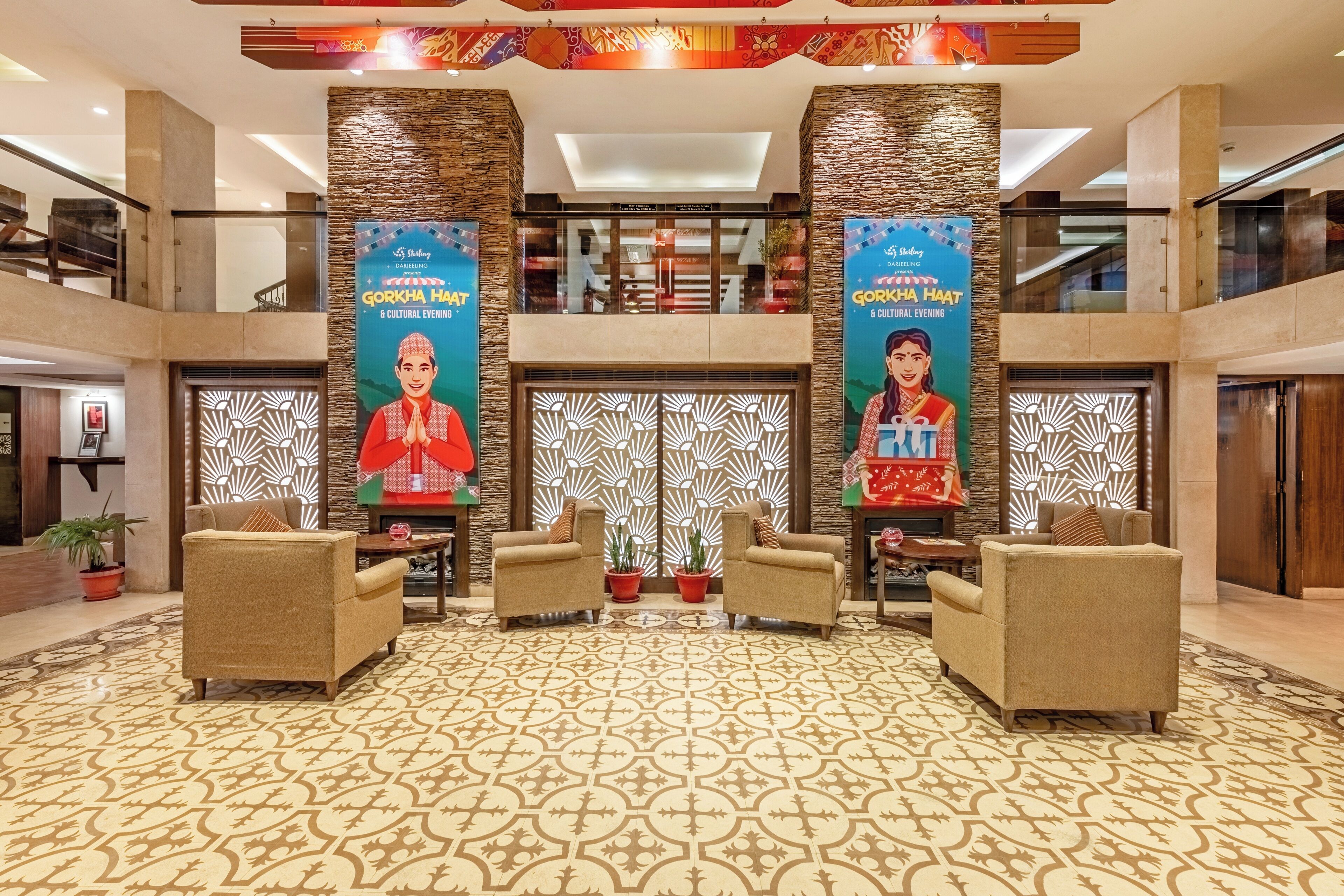 A lobby with patterned carpet, two sofas, a decorative wall, and a staircase.
