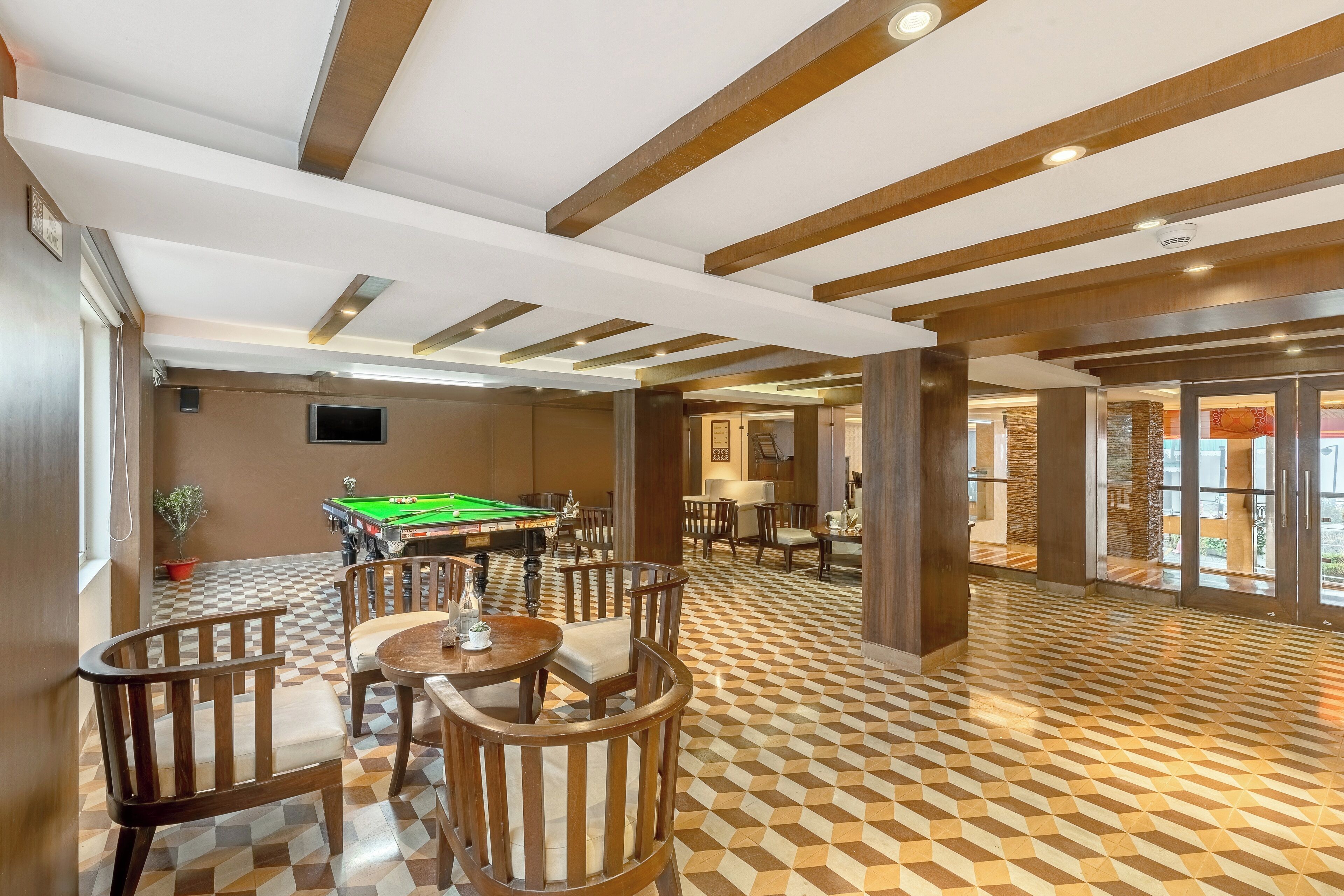 A billiards room with a pool table, wooden chairs, and a checkered floor.