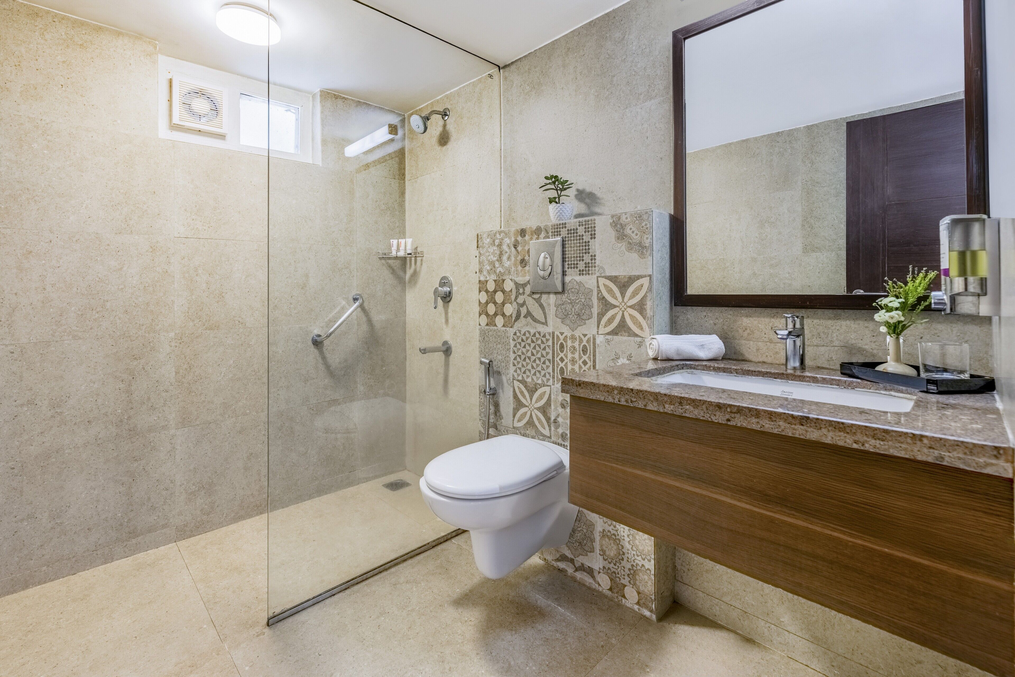 Ein modernes Badezimmer mit einer in Glas abgeschlossenen Dusche, einem Holzbadezimmer-Möbel und einem großen Spiegel.