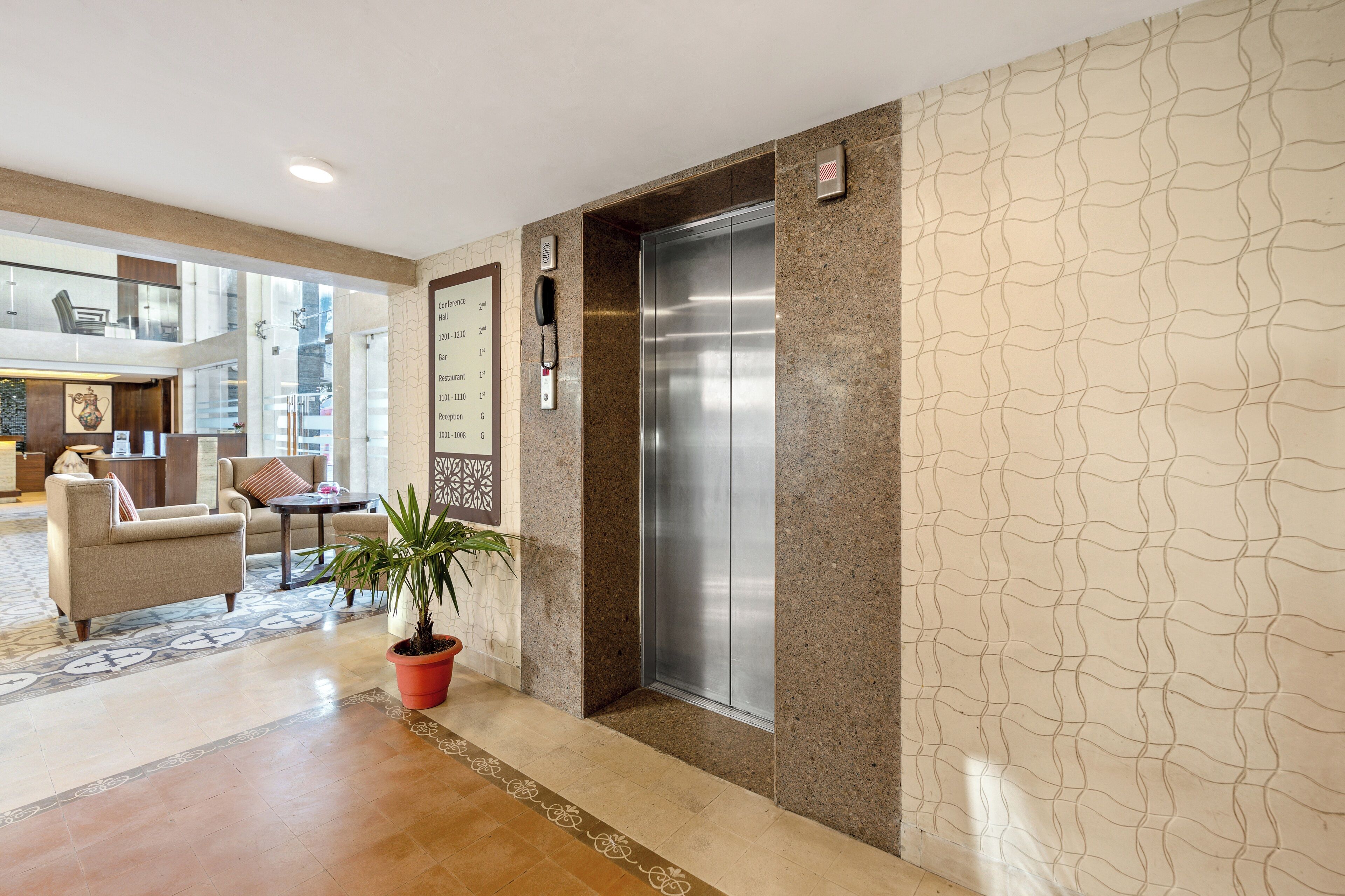 Un vestíbulo con mostrador de recepción, zona de estar y ascensor.