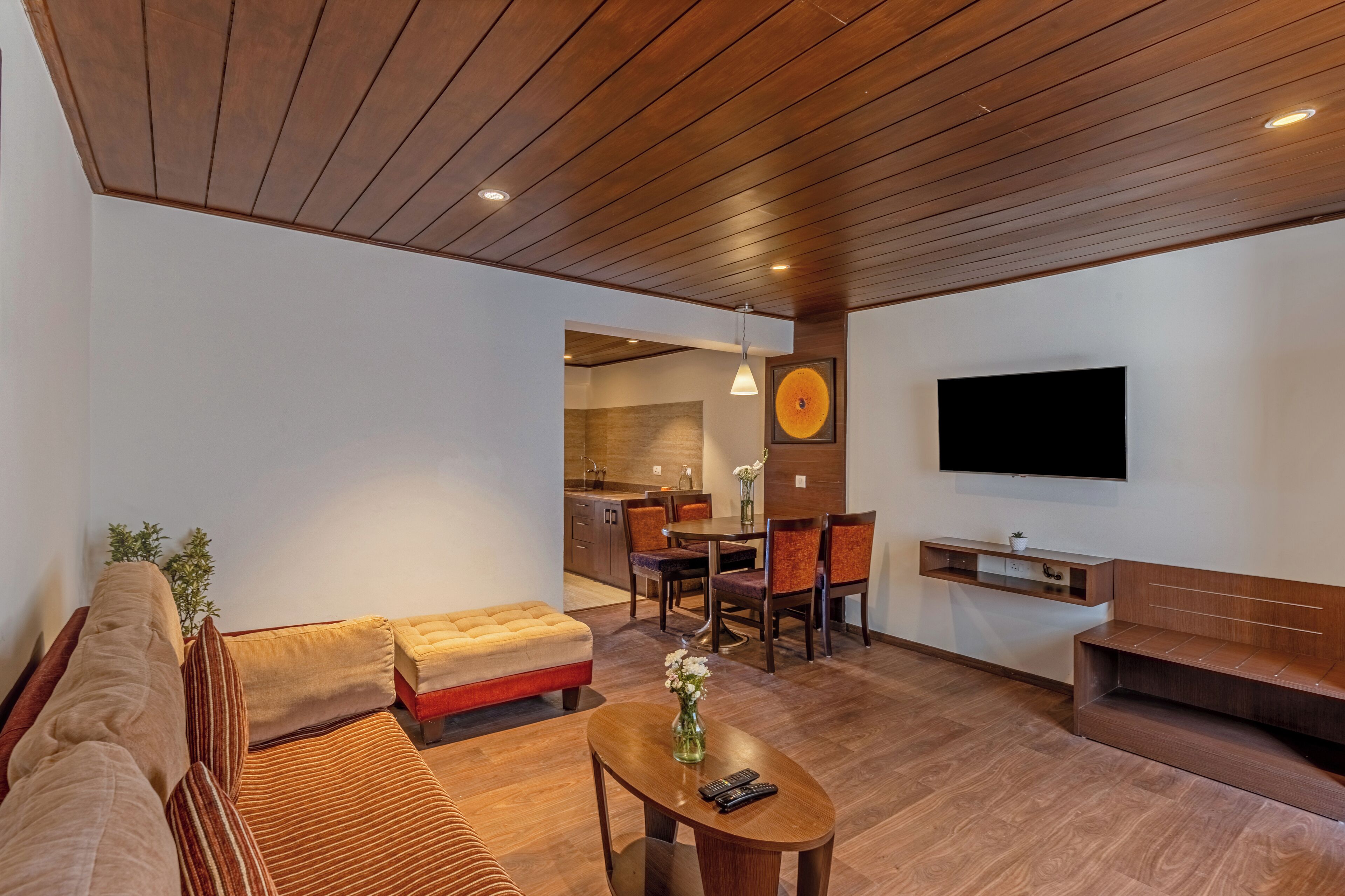 Un salon moderne avec un plafond en bois, un canapé, une table basse et un téléviseur fixé au mur.