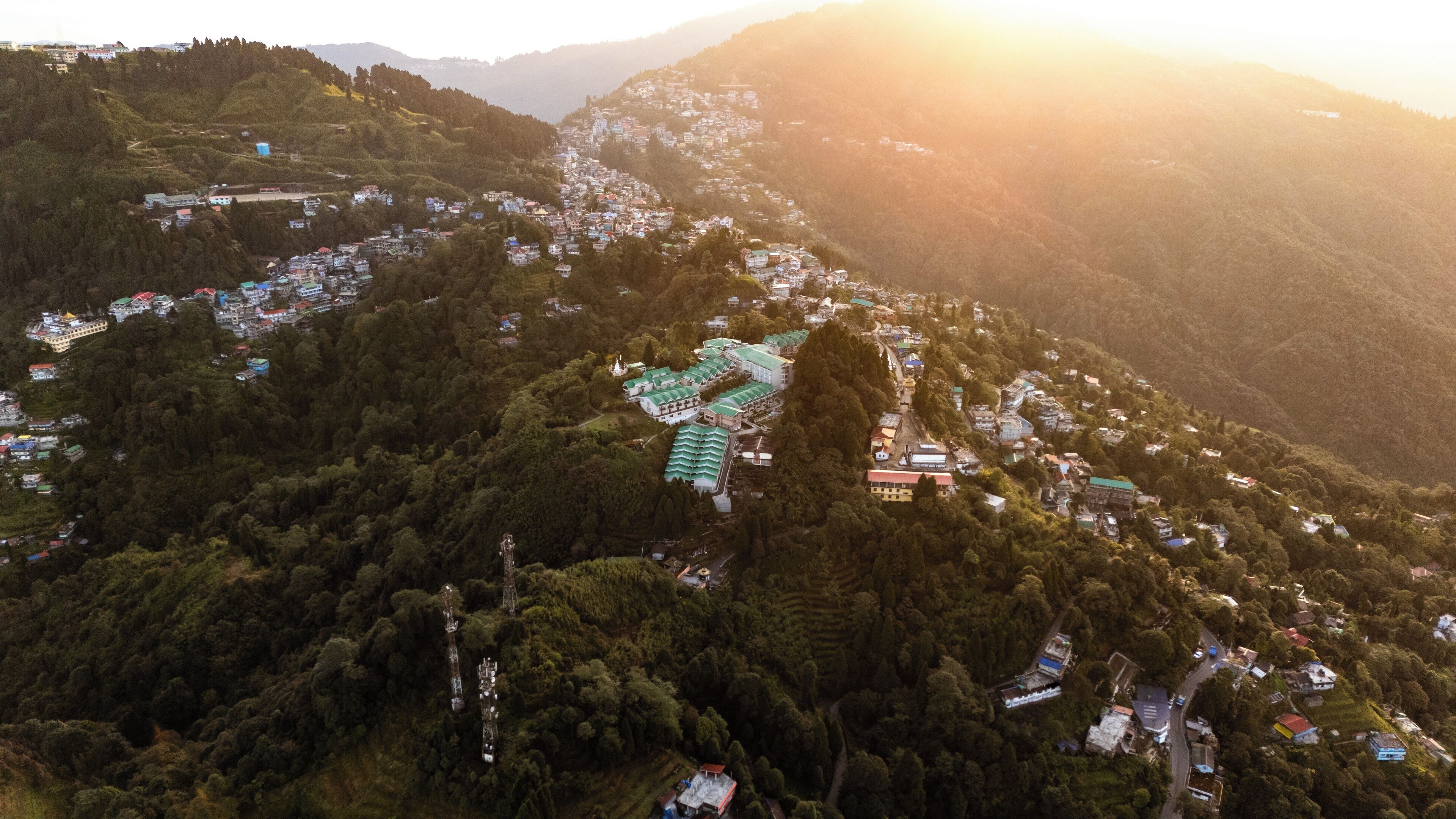 An aerial view of a mountainous village with terraced houses and a prominent building with a green roof.