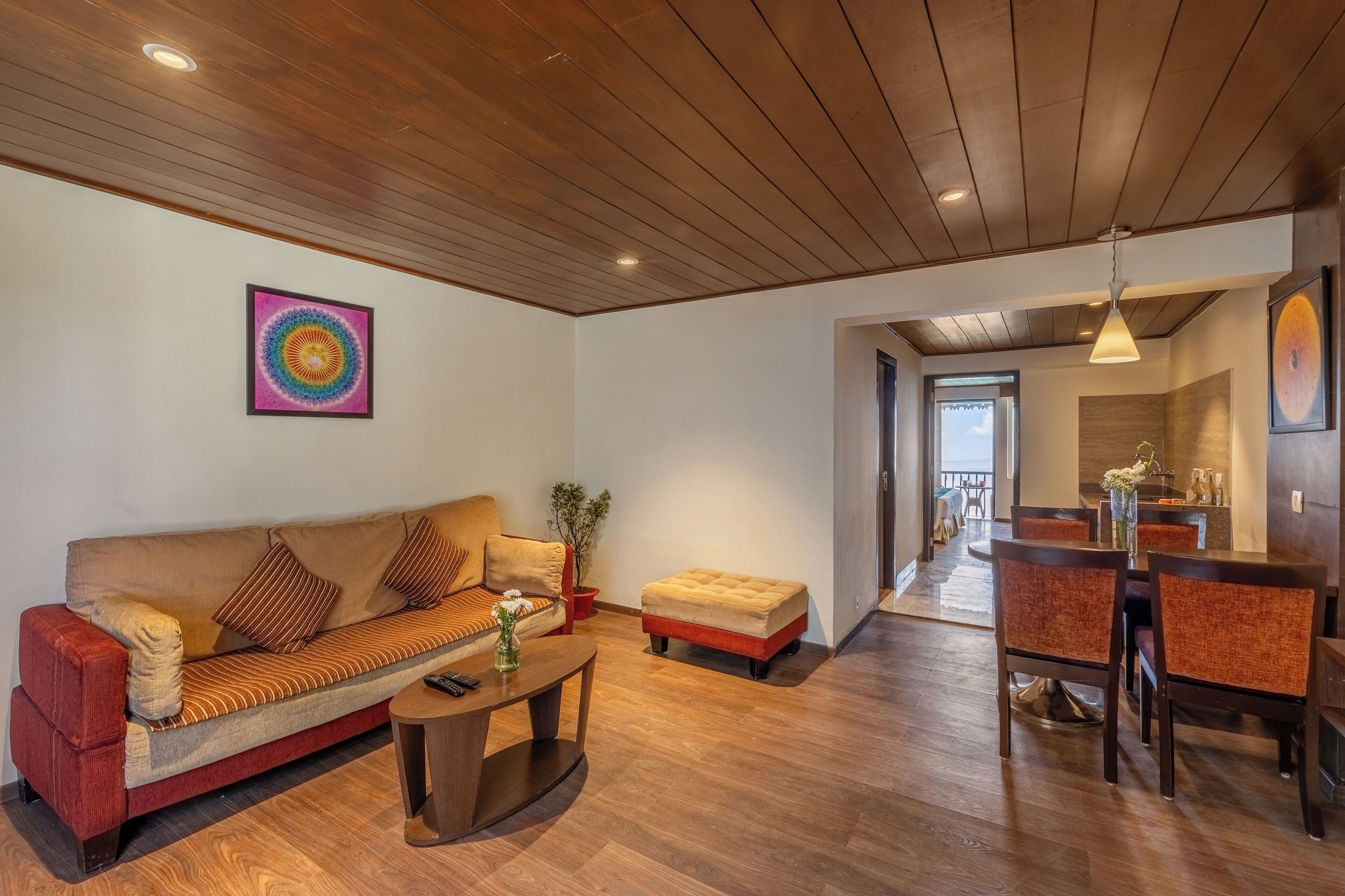 A modern living room with a wooden ceiling, a sofa, a coffee table, and a dining area with chairs and a table.