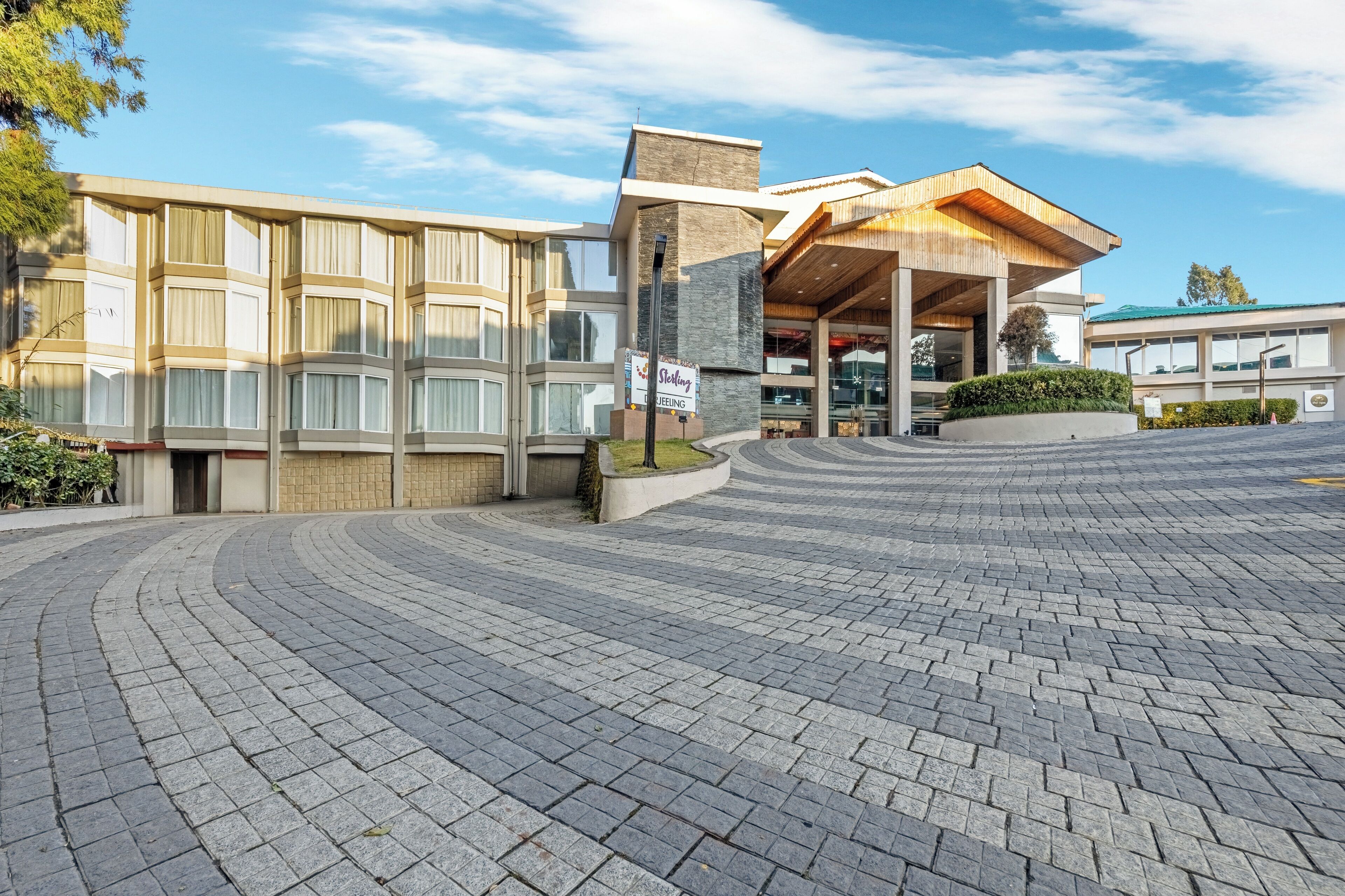 A hotel with a modern architectural design, featuring a curved driveway and a covered entrance area.