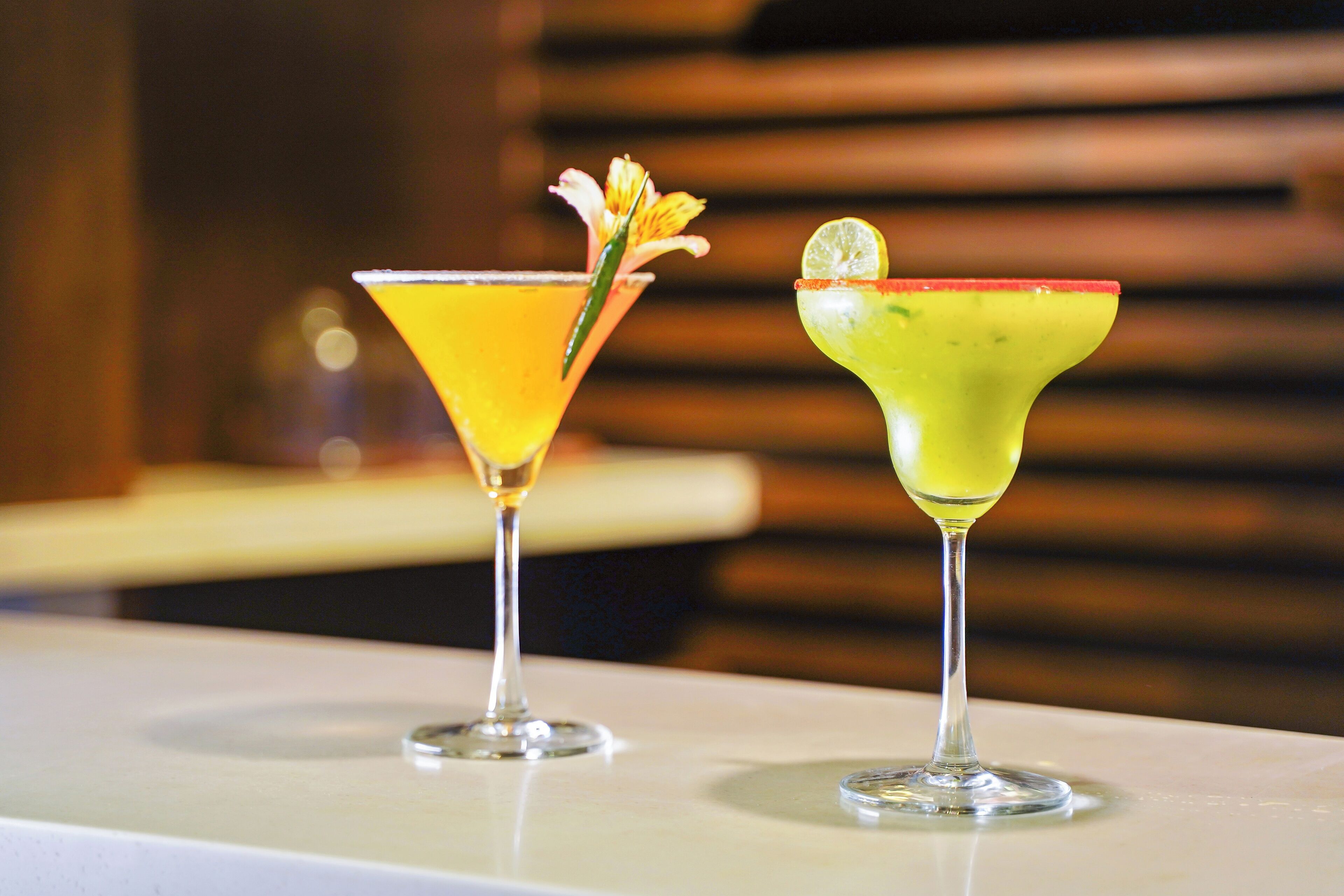 Zwei Cocktails auf einem weißen Tisch, unscharfer Hintergrund.
