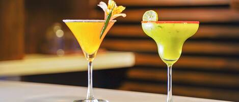 Two cocktails on a white table with a blurred background.