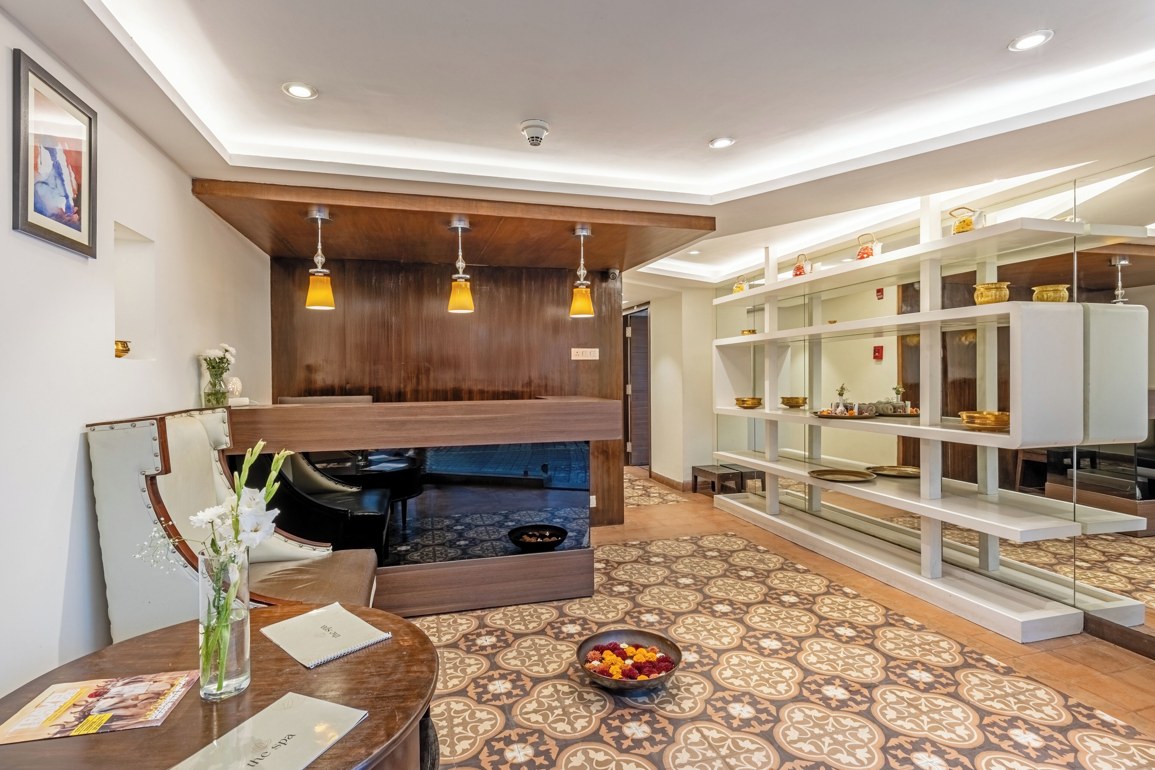 Un vestíbulo de hotel moderno con una zona de estar, un mostrador de recepción y una estantería decorativa con objetos.