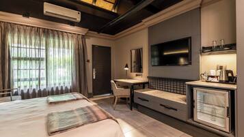 A hotel room with two beds, a desk, a TV, and a minibar.