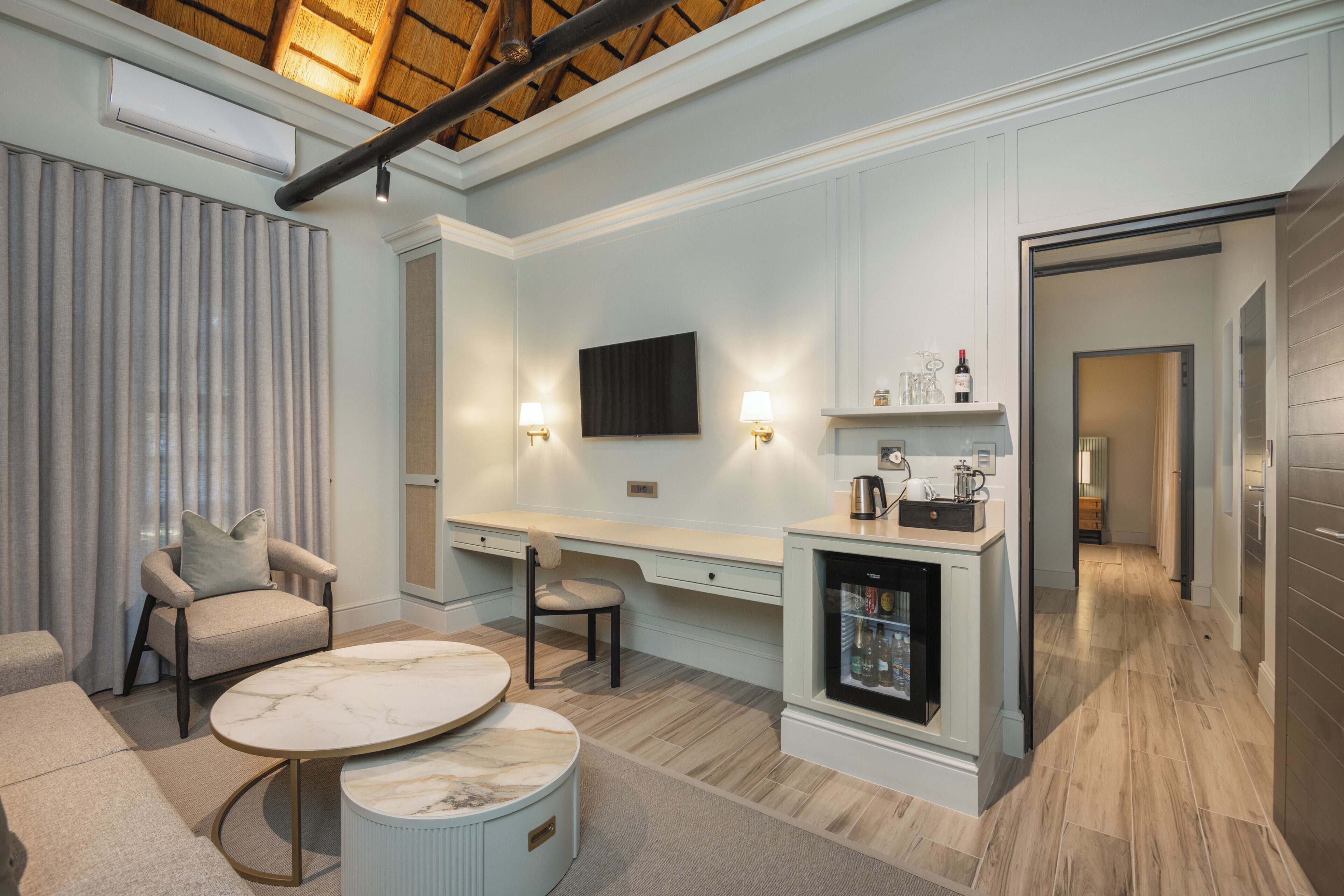 A modern living room with a marble coffee table, two armchairs, a built-in TV, and a mini-fridge.