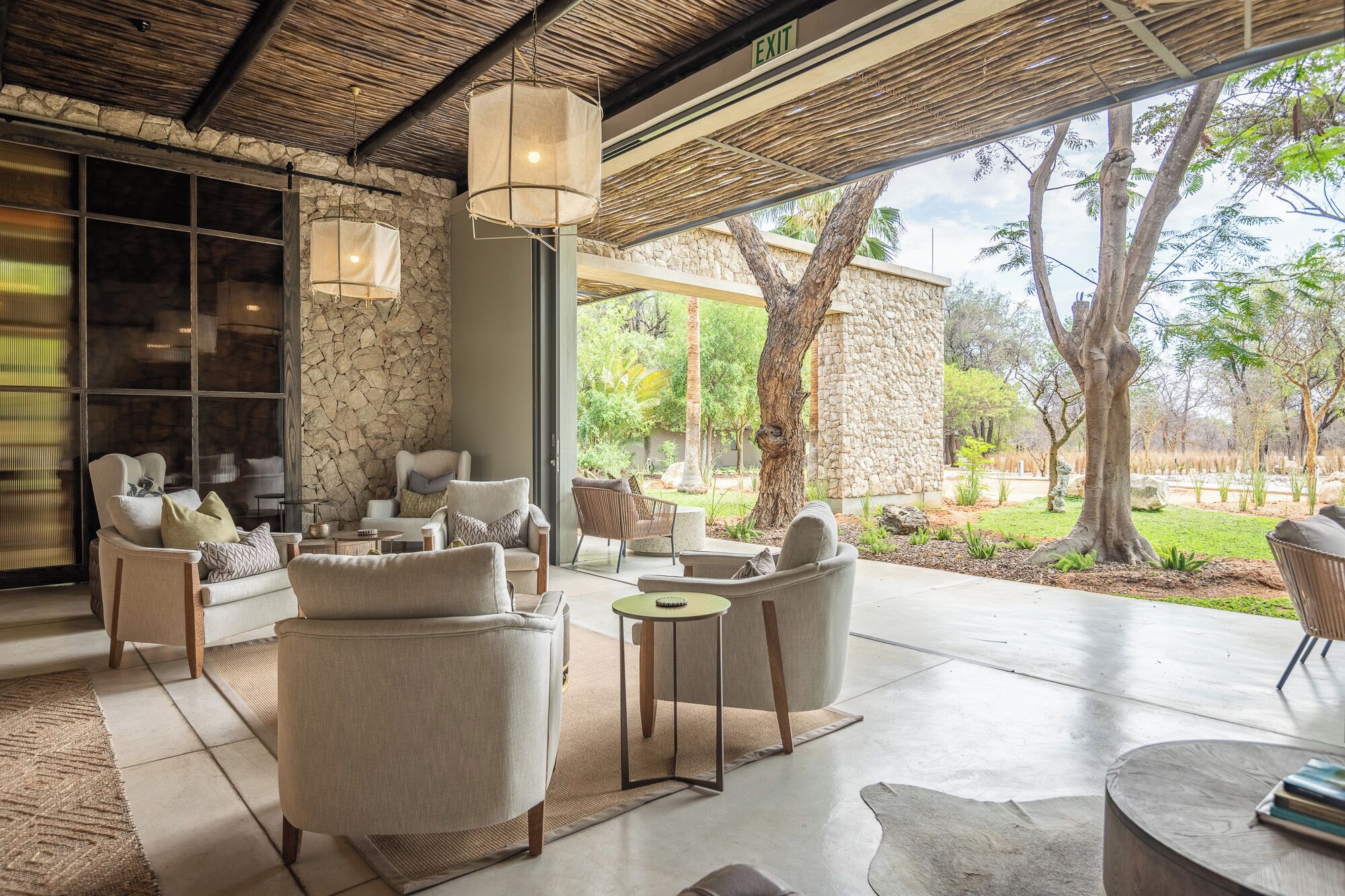 A spacious outdoor seating area with multiple chairs and tables, a stone wall, and a view of the surrounding landscape.