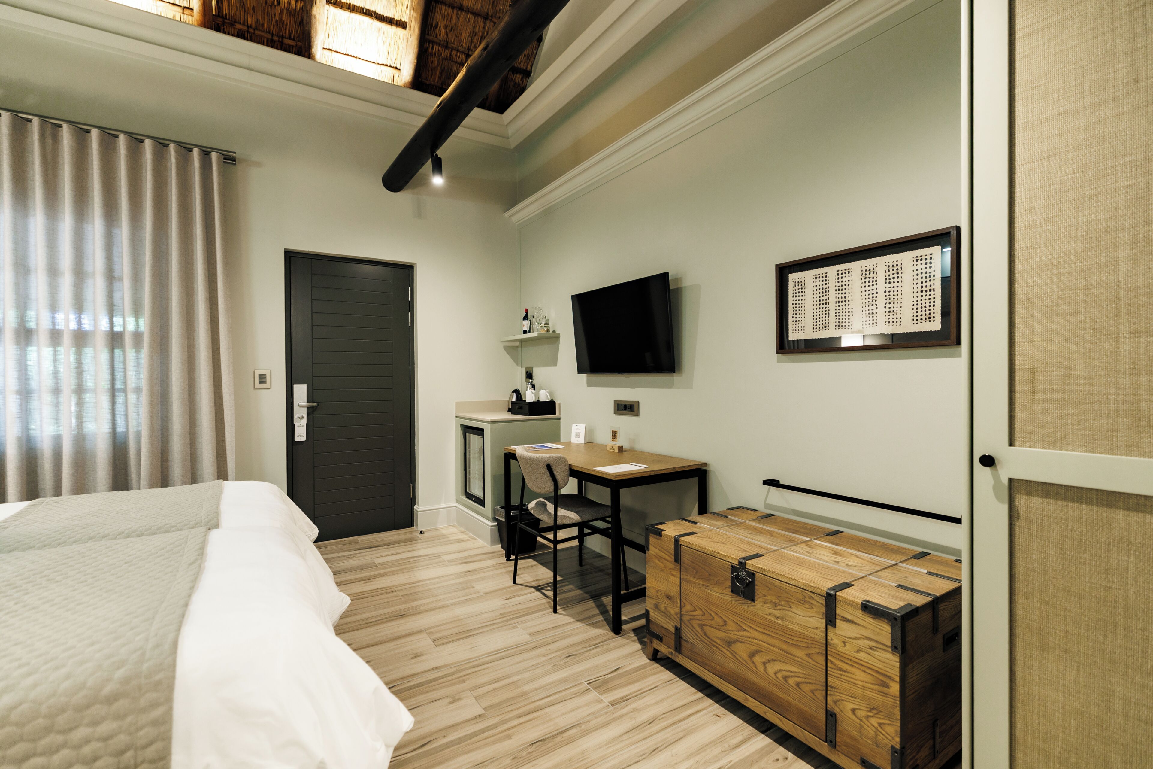 A hotel room with a bed, a desk, a chair, a television, and a wardrobe.