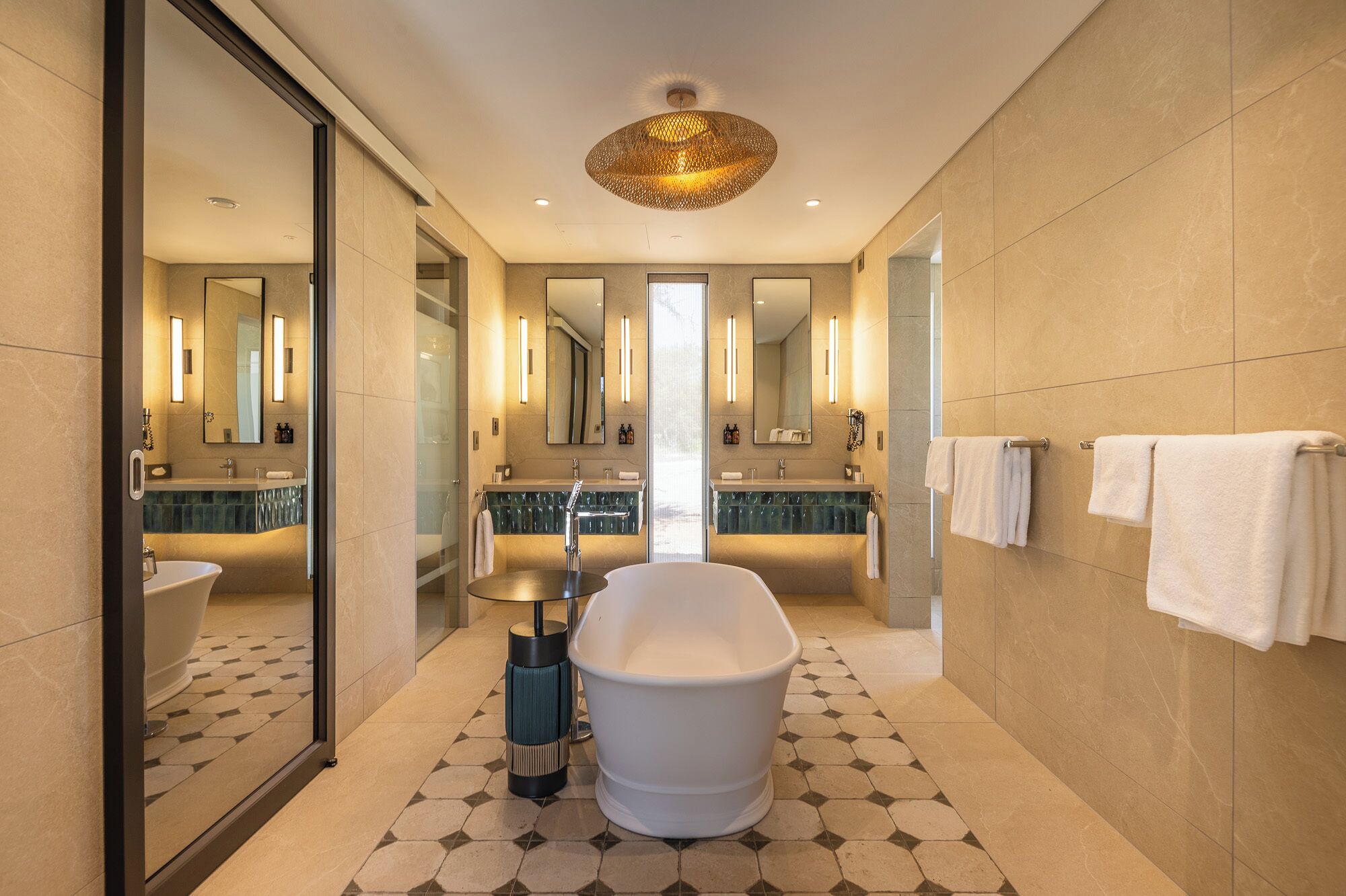 A modern bathroom with a freestanding bathtub, a large mirror, and a unique ceiling light fixture.