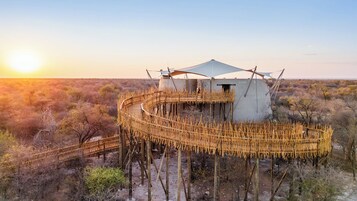 Una estructura circular de madera con un edificio central, rodeada por un paisaje natural.
