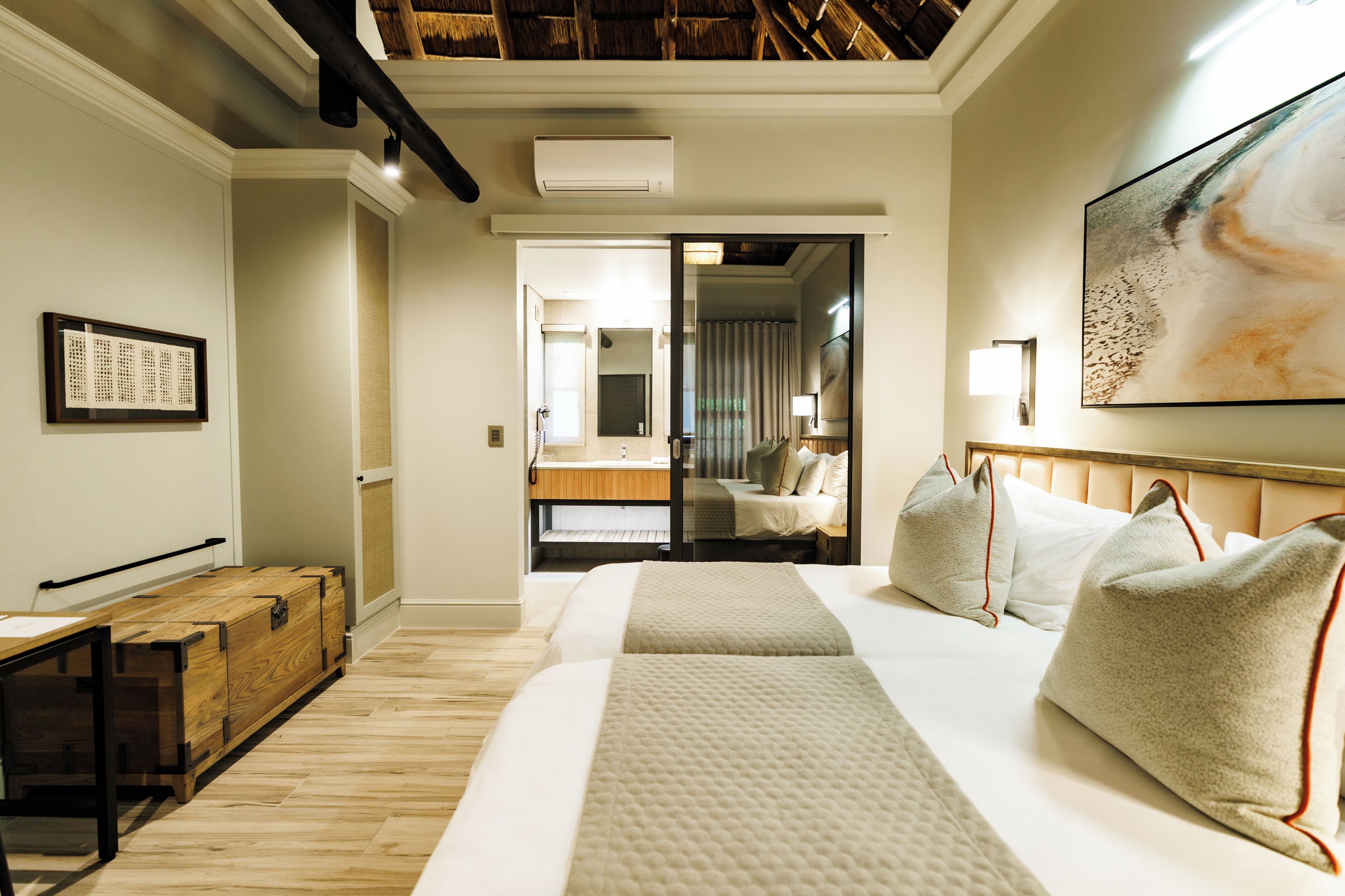 Una habitación de hotel con cama, mesita de noche y un ventanal grande.