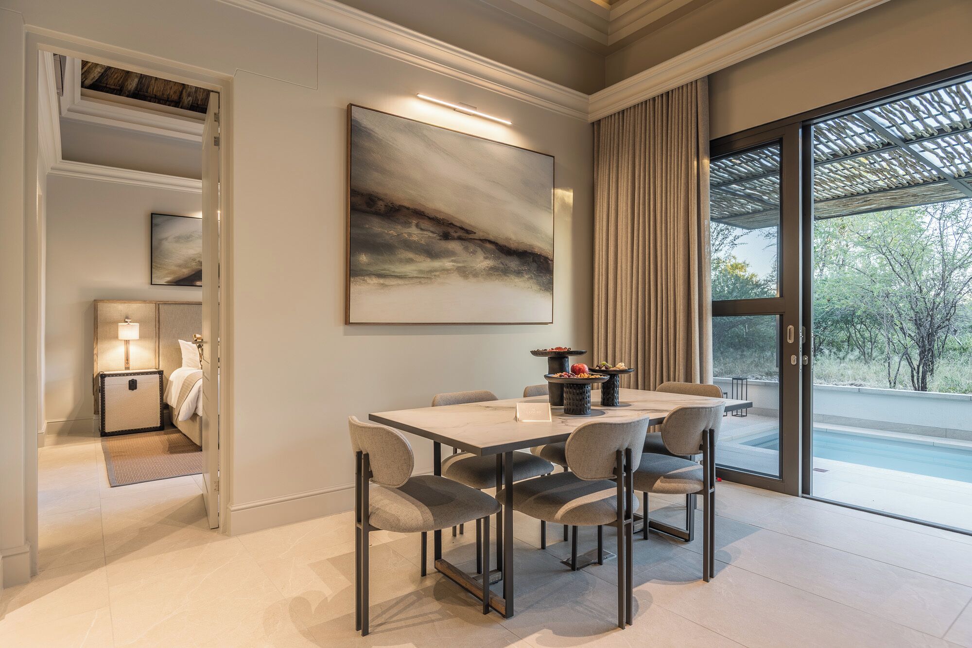 A dining area with a table, chairs, and a painting on the wall.