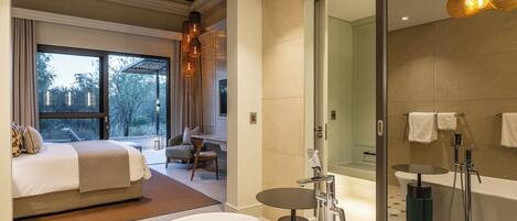 Une chambre d’hôtel moderne dotée d’un grand lit, d’un coin salon avec vue, d’une salle de bain séparée avec baignoire et d’un espace douche.