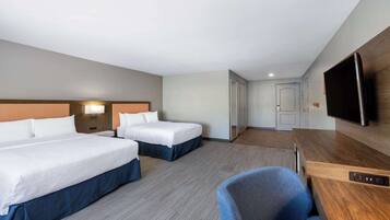 A hotel room with two beds, a TV, a desk, and a chair.