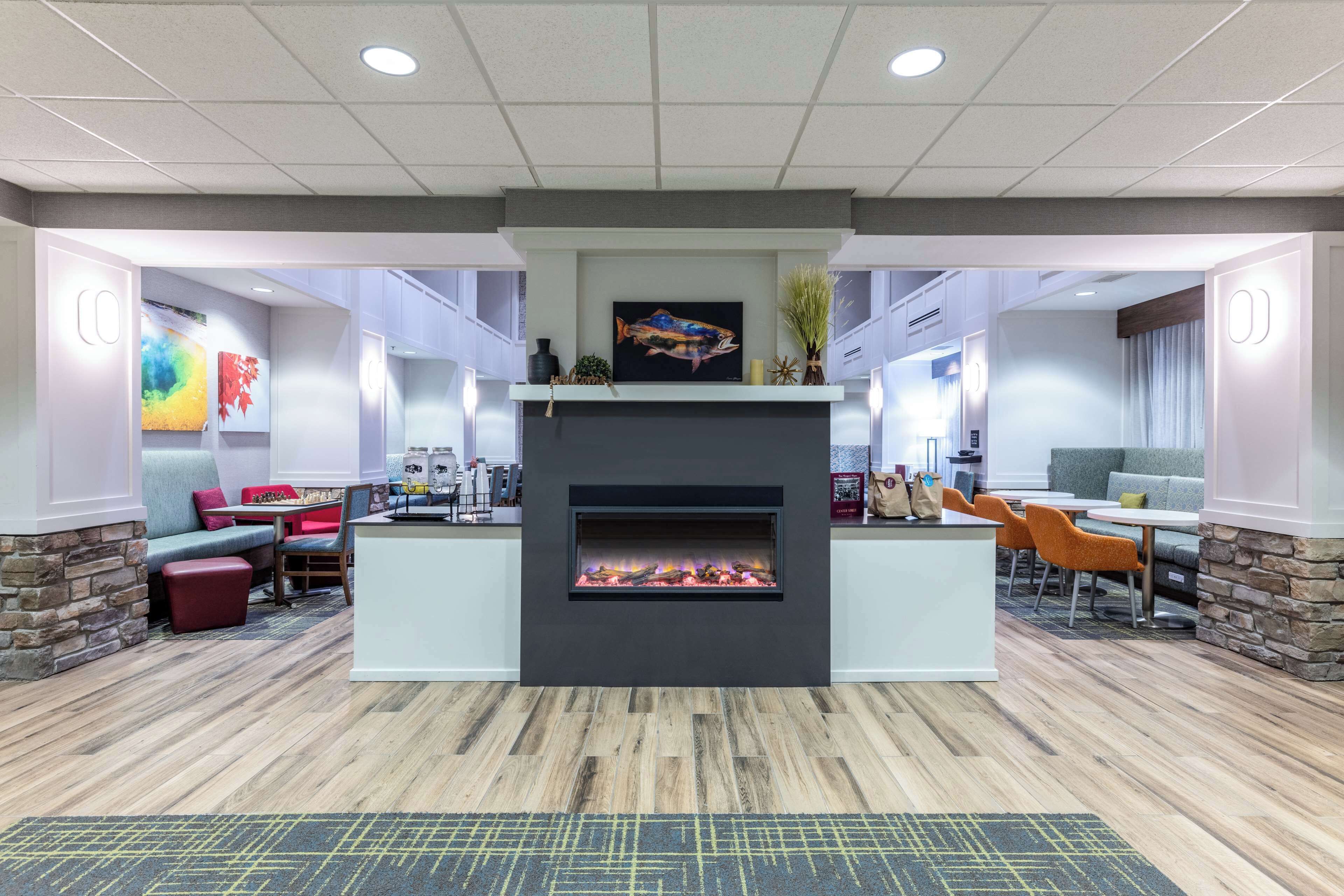 A modern lounge area with a fireplace, seating, and artwork.