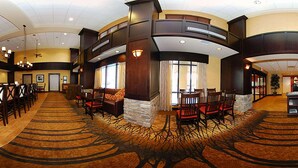 A spacious lobby with a high ceiling, a fireplace, and a seating area with leather chairs and ottomans. - Hampton Inn & Suites Casper (Casper)