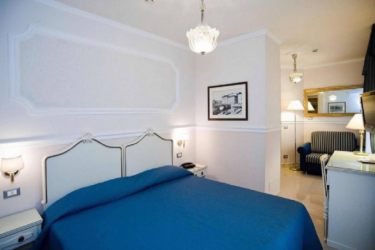 Une chambre d’hôtel comprenant un lit, une table de chevet, une lampe, une chaise et un miroir.