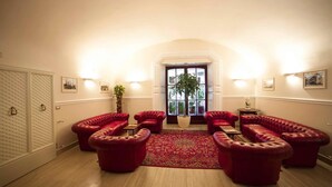 A spacious room with a red leather sofa set, a large window with a view, and a potted plant.