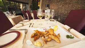 A dining table set with plates, cutlery, glasses, and a seafood dish.