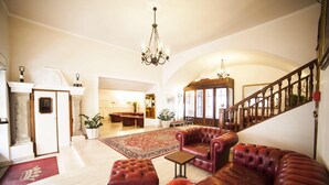 A spacious living room with a fireplace, leather sofas, a chandelier, and a staircase.