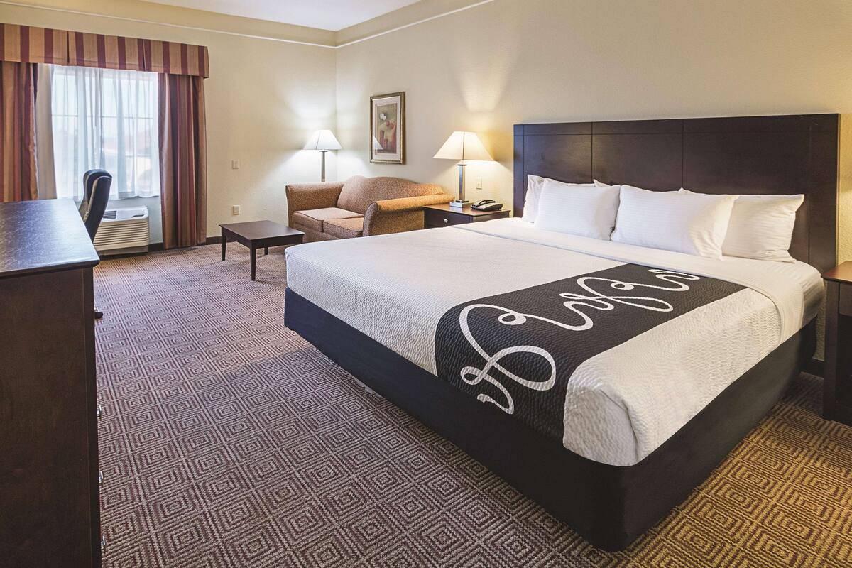 Una habitación de hotel con una cama grande, un escritorio, una silla y una mesita.