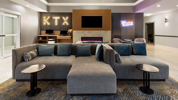 A modern living room with a sectional sofa, two side tables, a fireplace, and a TV mounted on the wall.