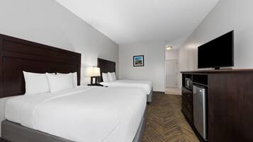A hotel room with two beds, a TV, a microwave, and a refrigerator.