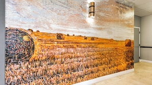 A large mosaic mural depicting a field with hay bales and a circular pattern on the left.