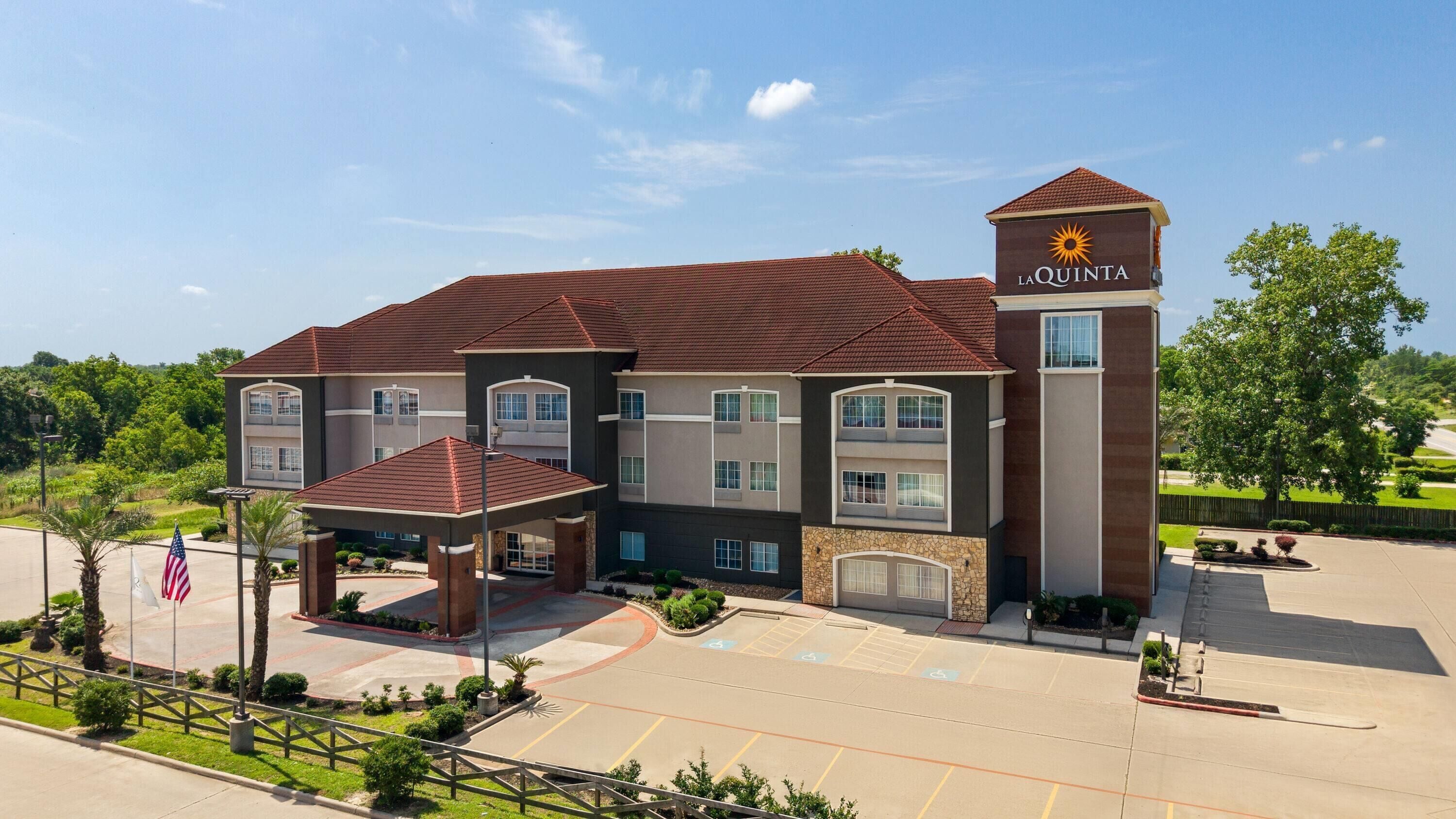 A multi-story hotel with a prominent entrance, a covered waiting area, and a parking lot with handicap-accessible spaces.