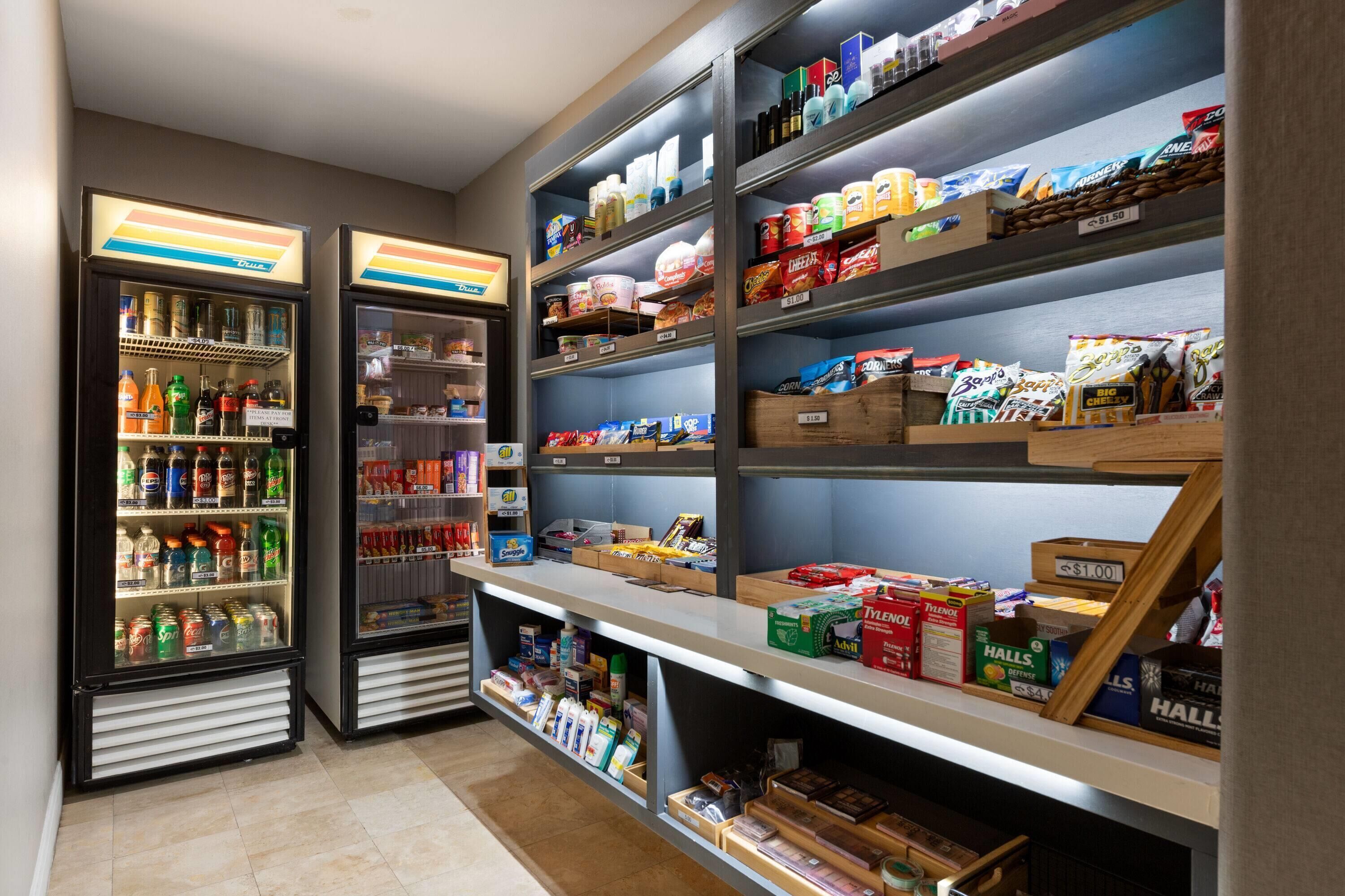 Un quiosco autoservicio para aperitivos y bebidas, con dispensadores de bebidas refrigeradas y estantes llenos de snacks y refrescos.