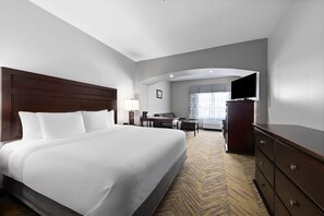 Habitación de hotel con una cama grande, un escritorio, una silla, un aparador y un televisor.