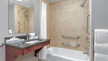 A modern bathroom with a bathtub, a shower with a glass door, a vanity with a granite countertop, and a mirror.