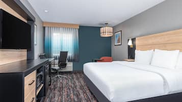 A modern hotel room with a bed, desk, chair, and a TV.