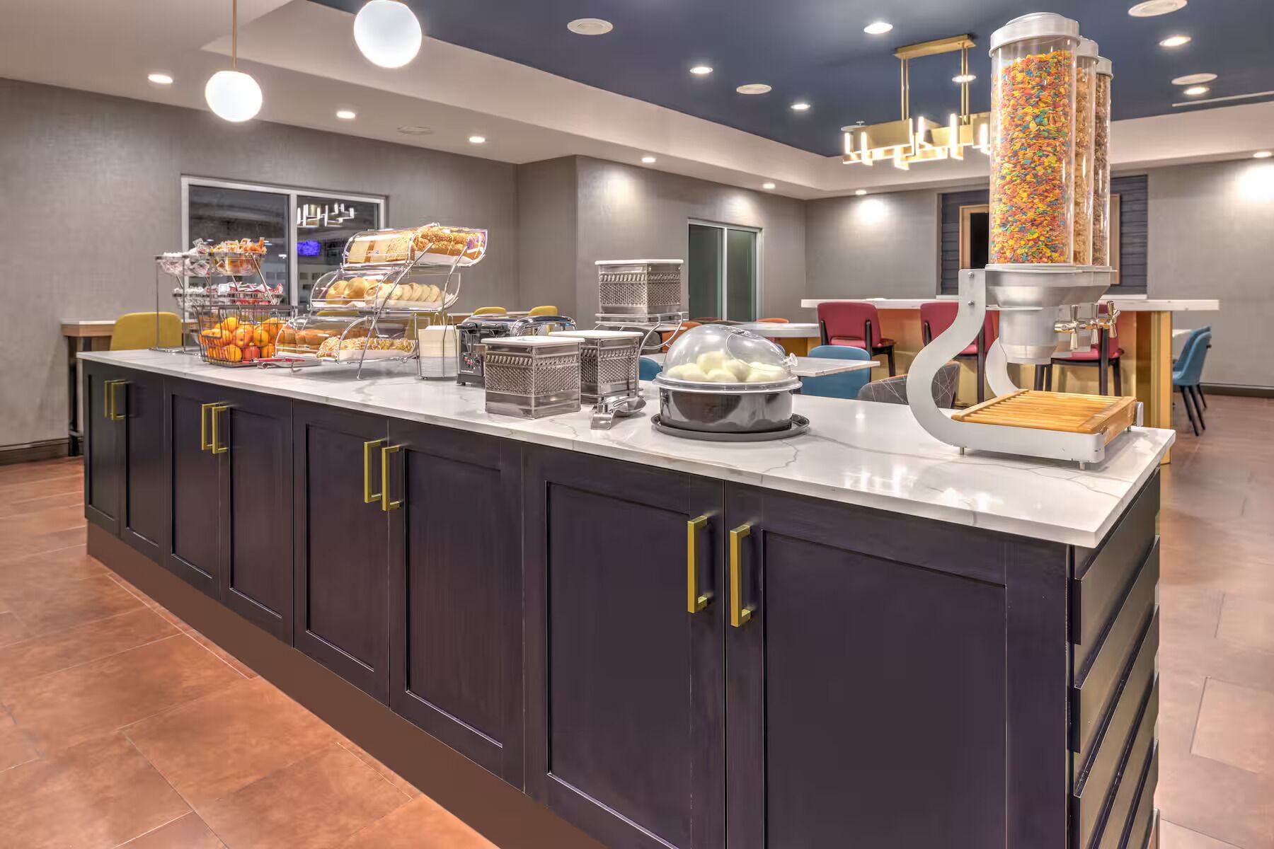 A modern breakfast bar with a variety of food items, including pastries, fruits, and a coffee machine.