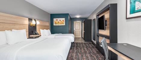 A hotel room with a large bed, a desk, a chair, a TV, and a painting on the wall.