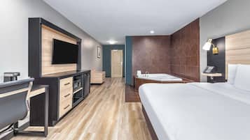 Une chambre d’hôtel moderne dotée d’un grand lit, d’un bureau avec une chaise, d’une télévision, d’une salle de bain avec baignoire et d’une table de chevet avec une lampe.